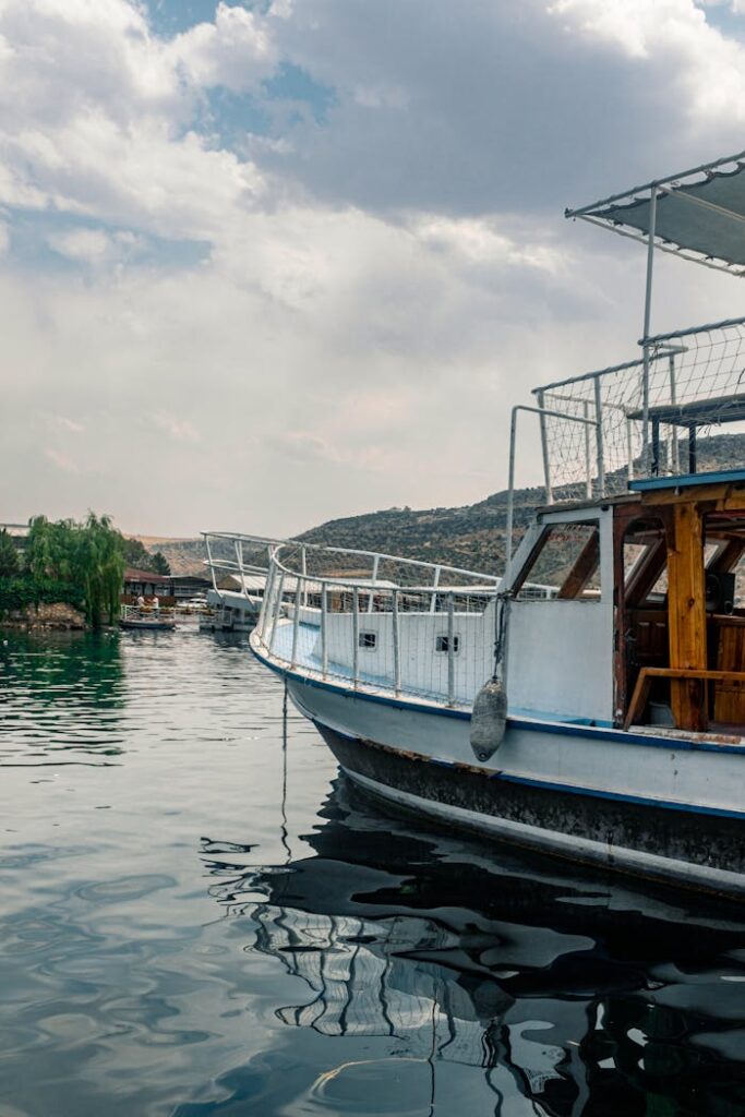 A peaceful scene of a boat on a tranquil lake with hills in the background under a cloudy sky.