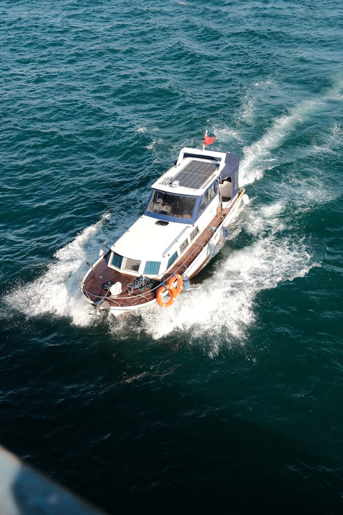 Aerial shot of a small yacht cruising through turquoise waters on a sunny day.