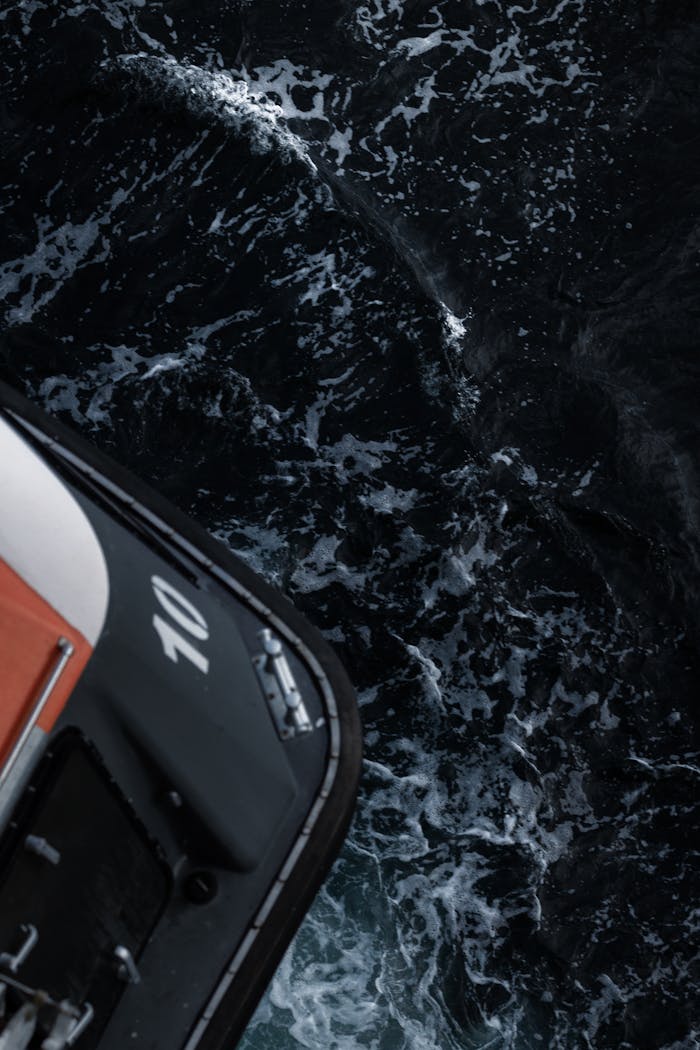 Crafting Captivating Headlines: Your awesome post title goes here A dramatic aerial shot of a boat navigating through dark ocean waters, showing its interaction with waves.