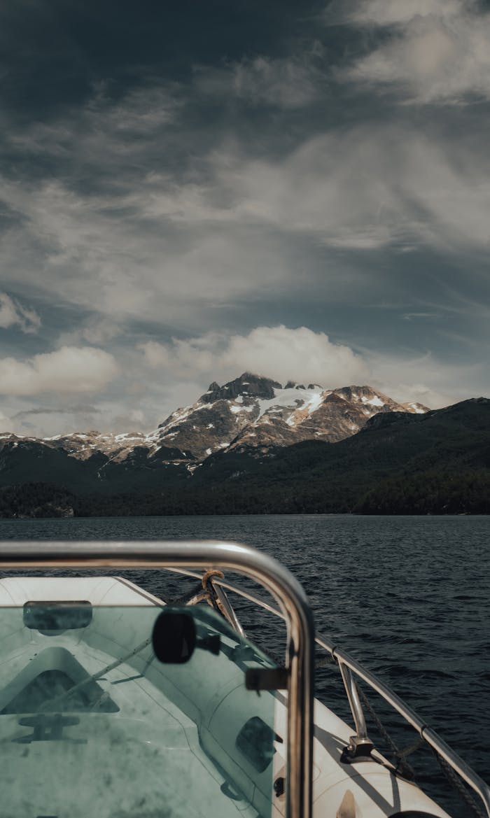 A tranquil boat ride offers stunning views of snow-capped mountains under a cloudy sky.